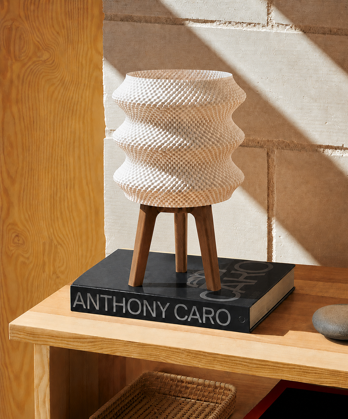 Ngaru sculptural table lamp in matte white on a wood shelf beside a book, LAYR, made in New Zealand